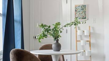 Un comedor moderno con una mesa redonda blanca, una silla tapizada marrón, una planta en maceta y una alfombra de piel de vaca.