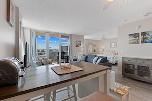 A modern apartment with a balcony, a dining area, and a living room. - Estero Beach & Tennis 802c - Beach Sunrise (Fort Myers Beach)
