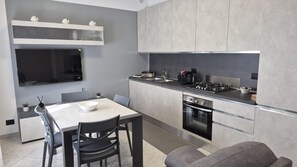 Cozinha moderna com área de refeições, eletrodomésticos embutidos e televisão de tela plana.