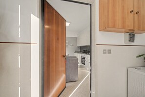 A modern kitchen with a built-in oven and a grey sofa in the adjacent living area.