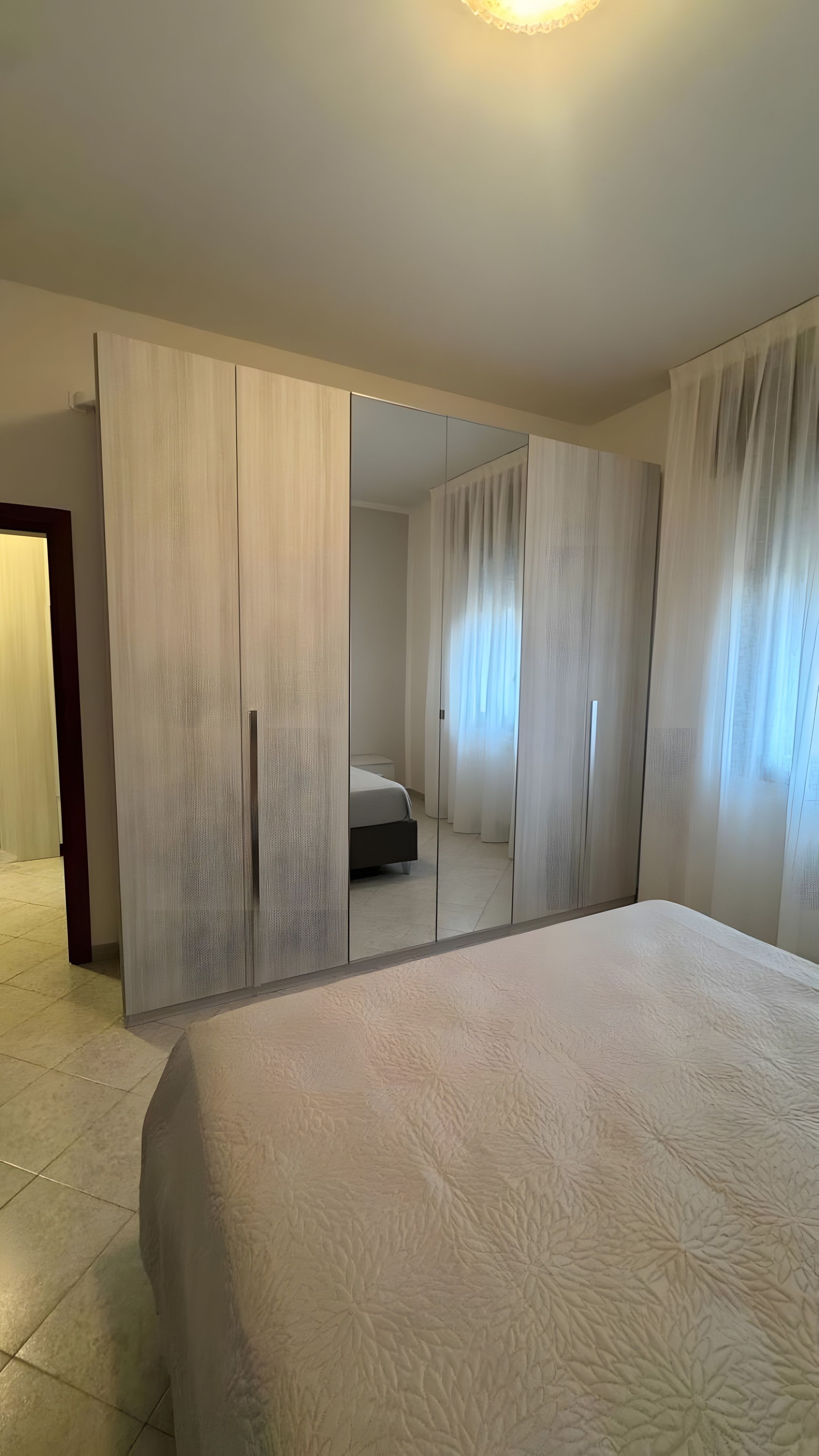 A bedroom with a large bed, a wardrobe, and a mirror.