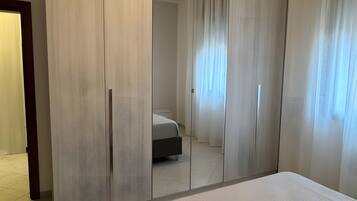 A bedroom with a large bed, a wardrobe, and a mirror.