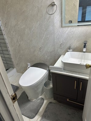 Casa de banho com sanita, lavatório e espelho na parede.