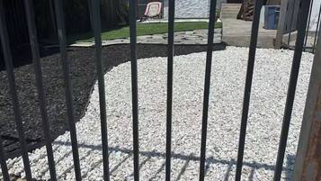 A fenced outdoor area with gravel and a stone pathway.