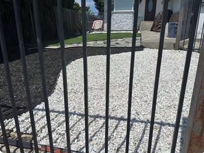 Área externa cercada com brita e um caminho de pedras.