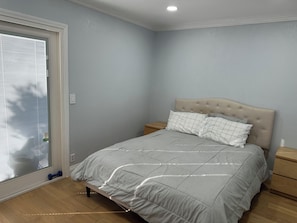 A bedroom with a bed, a nightstand, a window with blinds, and a door. - Spacious 3-bedroom house in charming Hayward with AC/Heat near Cal State Eastbay (Hayward)