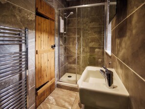 A modern bathroom with a glass shower enclosure, a wooden door, and a white sink. - Mauldslie Hill Cottage - Sleeps 6 and Pet Friendly (Gorebridge)