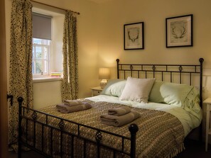 A neatly made bed with folded towels, a bedside lamp, and two framed pictures on the wall. - Mauldslie Hill Cottage - Sleeps 6 and Pet Friendly (Gorebridge)