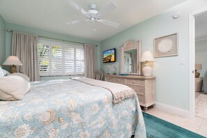 Une chambre à coucher avec un lit, une commode, un miroir et un ventilateur de plafond.