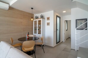 A modern living room with a dining area, a white cabinet with glass doors, and a staircase. - Holiday Home in Nerja With Sea Views (Nerja)