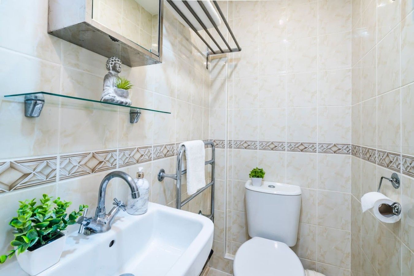 A bathroom with a glass shelf, a sink, a toilet, and a mirror.
