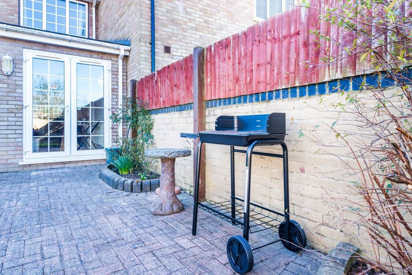 Eine Terrasse mit Grill, Steintisch und Backsteinmauer.