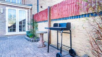 Un patio con una parrilla, una mesa de piedra y un muro de ladrillo.