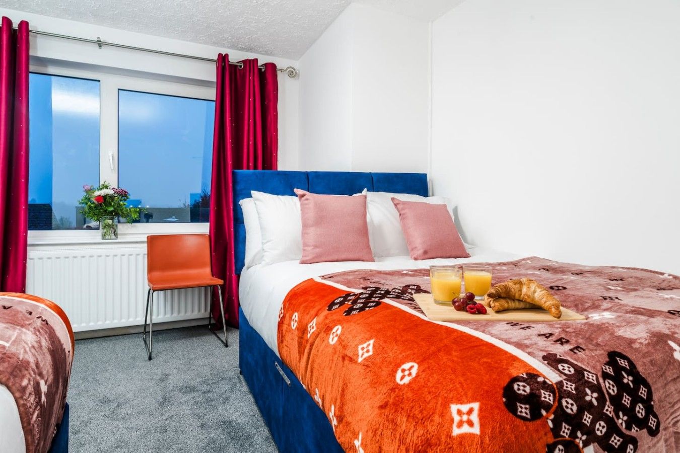 A hotel room with a bed, a desk, and a window with curtains.