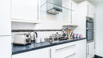 Una cocina moderna con armarios blancos, estufa a gas, tostadora y microondas.