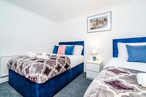 Ein Hotelzimmer mit zwei Betten, einem Nachttisch mit Lampe und einem gerahmten Bild an der Wand.