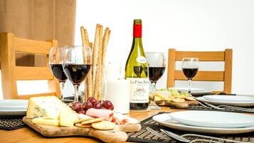 A table set for a meal with cheese, crackers, grapes, and wine glasses.