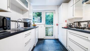 A modern kitchen with white cabinetry, a black countertop, and a view to the outside.