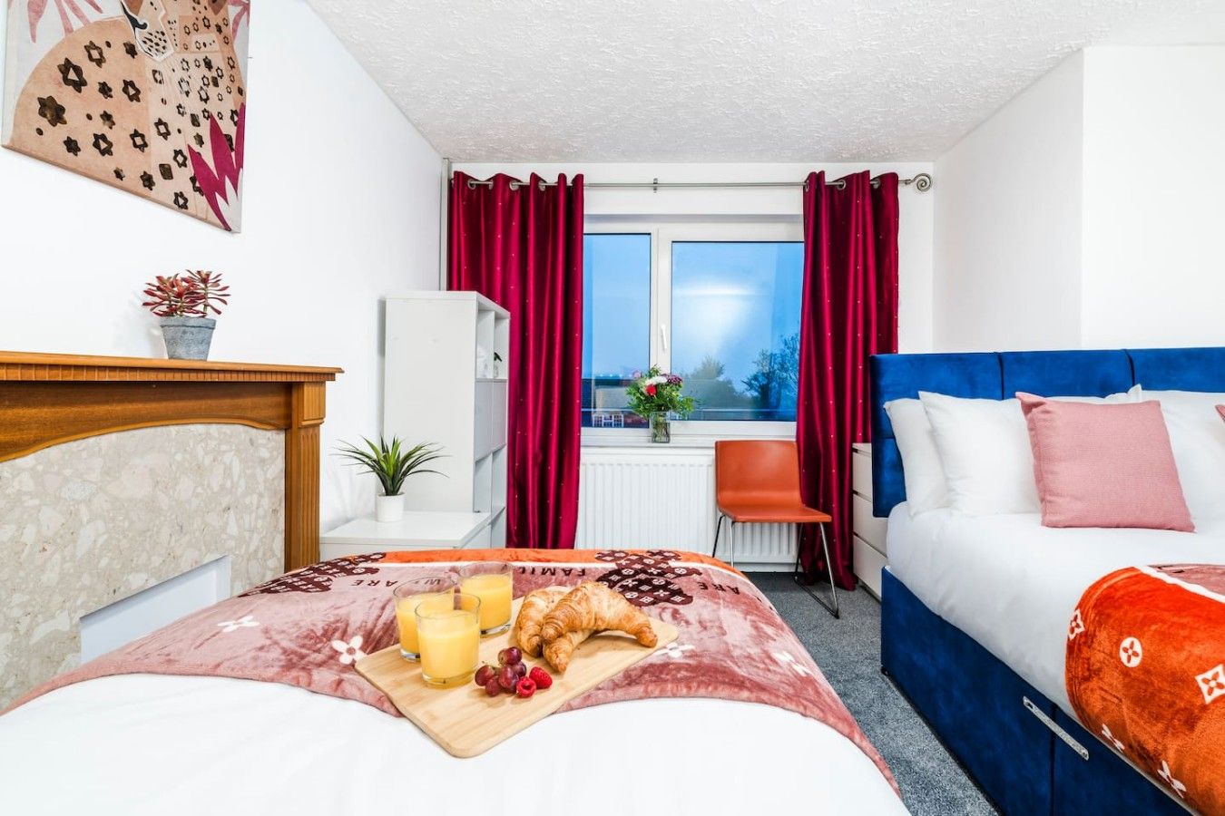 Habitación de hotel con cama, sofá, ventana con cortinas, una mesita con provisiones para el desayuno y vistas al exterior.