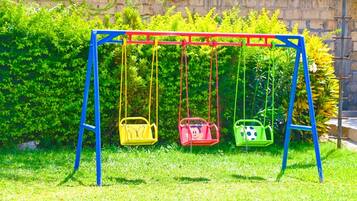 Een schommel met drie schommelstoelen in verschillende kleuren.