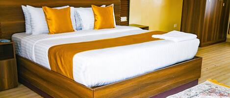 A large bed with a wooden frame, white bedding, and two yellow pillows.