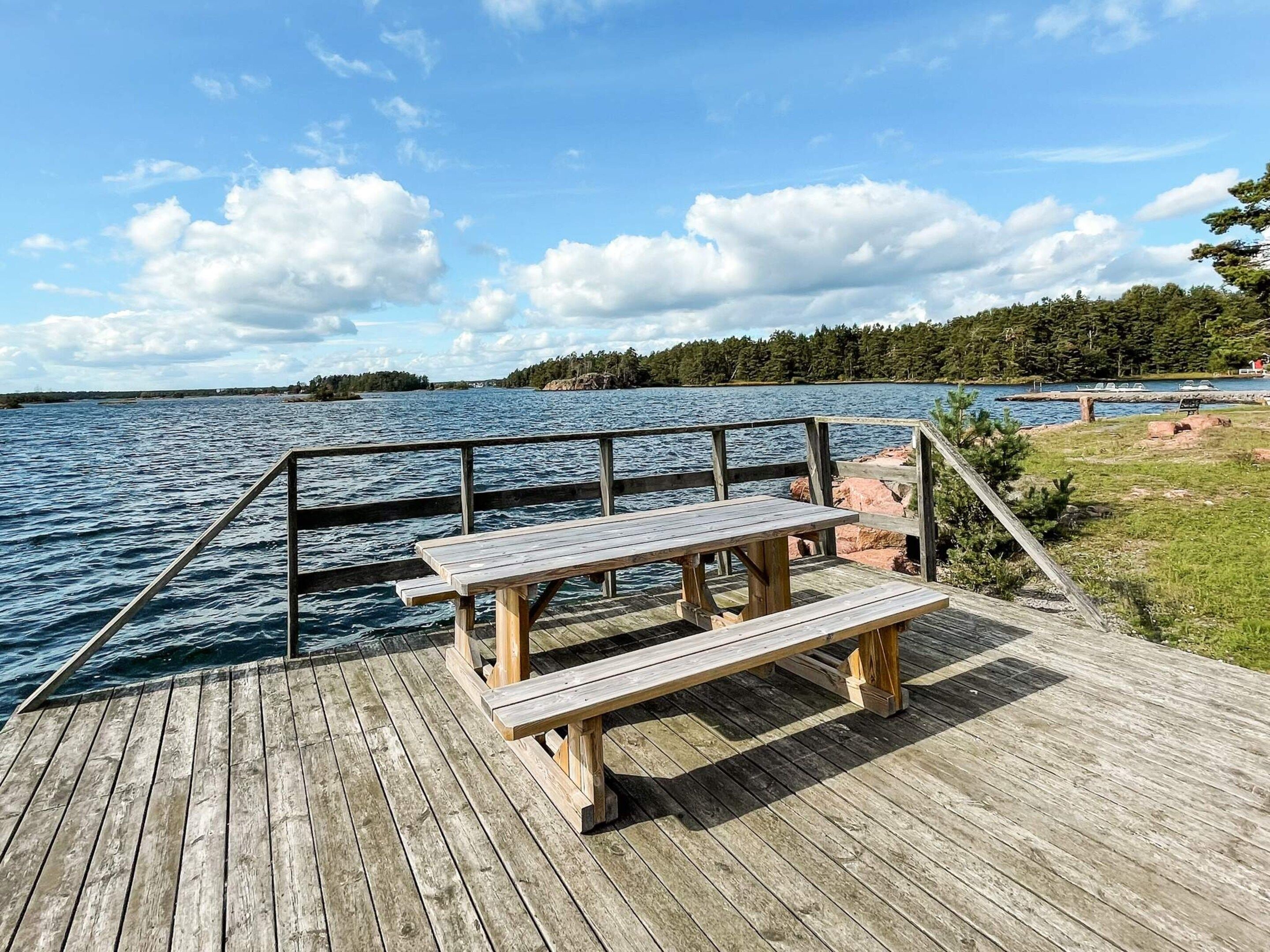 A wooden dock with a picnic table and benches overlooking a body of water.