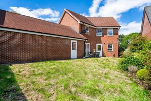 A residential property with a brick exterior, a front door, and a small patio area with outdoor furniture. - Argus 4-Bed Premium in Hemel: Contractor, Families (Hertfordshire)