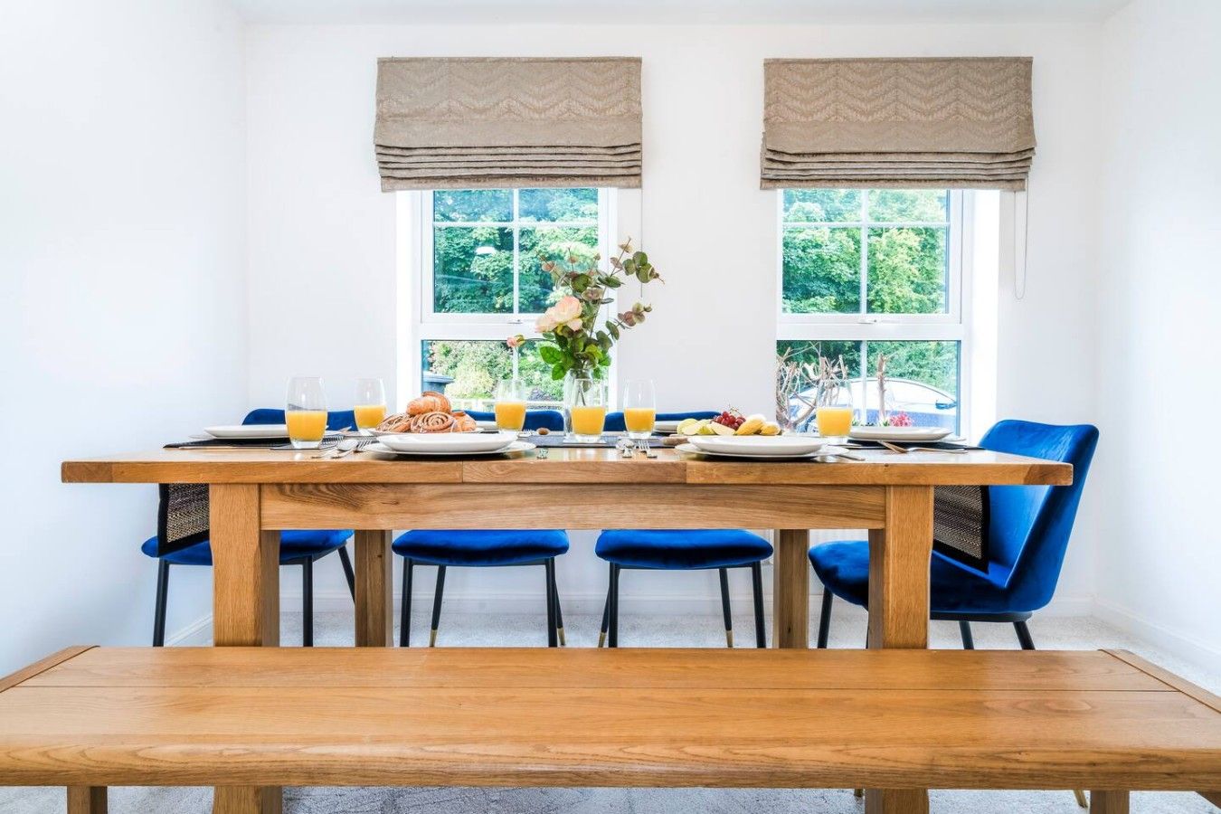 A dining area with a wooden table, blue chairs, and a bench.
