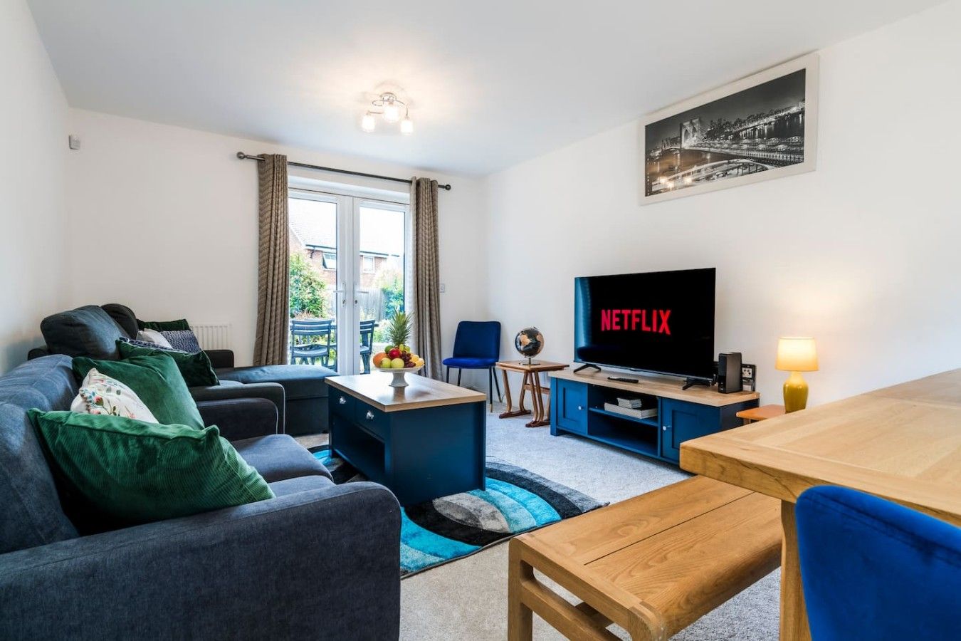 A modern living room with a sofa, a coffee table, a TV, and a dining area.