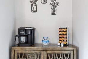 A kitchenette with a coffee maker, water bottles, and a fruit dispenser on a wooden cabinet. - Perfect/private location between Gatlinburg/Pigeon Forge on top of the ridge. (Sevierville)