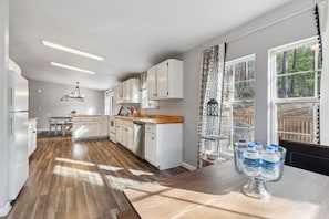 A modern kitchen with white cabinets, a wooden countertop, and a dining area with a table. - Perfect/private location between Gatlinburg/Pigeon Forge on top of the ridge. (Sevierville)