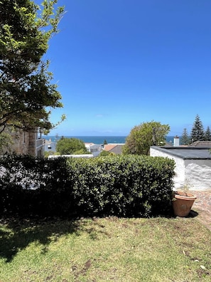 A residential area with a view of the sea, a stone building, and a well-maintained lawn. - The Original Kalk Bay Farmhouse at the Homestead (Cape Town)