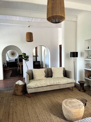 A cozy living room with a sofa, a woven rug, and a round wooden table. - The Original Kalk Bay Farmhouse at the Homestead (Cape Town)
