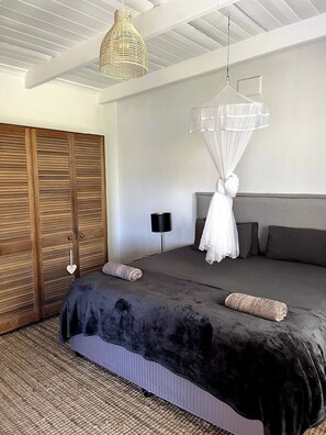 Une chambre à coucher comprenant un lit, un luminaire suspendu, une armoire et une table de chevet.