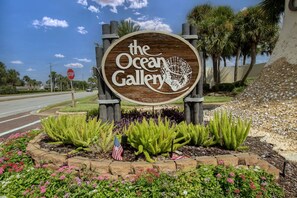 A wooden sign with the text 'the Ocean Gallery' surrounded by a landscaped garden with various plants and a small American flag. - Del Lago - 3 Minutes walk to the Beach (St. Augustine)