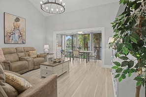 A spacious living room with a sofa, coffee table, and a painting on the wall. - Del Lago - 3 Minutes walk to the Beach (St. Augustine)