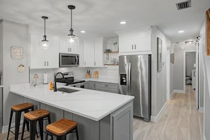 A modern kitchen with a central island, stainless steel appliances, and pendant lighting. - Del Lago - 3 Minutes walk to the Beach (St. Augustine)