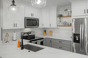 A modern kitchen with white cabinets, a stainless steel refrigerator, a microwave, an oven, and a sink. - Del Lago - 3 Minutes walk to the Beach (St. Augustine)