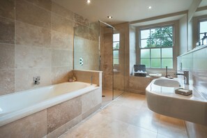 A modern bathroom with a large bathtub, a separate shower area, and a vanity with a sink. - Three Mile House (Carnforth)