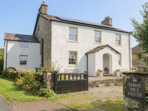 A white building with a black gate, a stone wall, and a sign that reads 'THREE MILE HOUSE'. - Three Mile House (Carnforth)