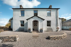 A two-story white building with a central entrance, stone steps leading to the door, and a gravel driveway. - Three Mile House (Carnforth)