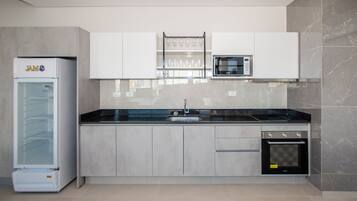 Cuina moderna amb nevera integrat, microones, forn i una prestatgeria de vidre per a vi.