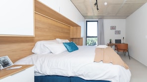 Un dormitorio moderno con una cama grande, un escritorio y vistas al exterior.