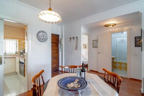 A dining area with a round table, chairs, a decorative bowl, and a hanging light fixture. - Apartment in Nerja Near Scenic Beaches (Nerja)