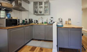 A modern kitchen with grey cabinets, a microwave, a stove, and a coffee maker. - CONTEMPORARY FLORENCE APARTMENT WITH 3 BEDROOMS & 3 BATHROOMS (Firenze)