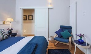A bedroom with a bed, a chair, a nightstand, and a wall-mounted lamp. - CONTEMPORARY FLORENCE APARTMENT WITH 3 BEDROOMS & 3 BATHROOMS (Firenze)