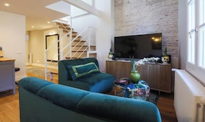 Una sala de estar moderna con un sofá, un televisor y una escalera que lleva a otra habitación.