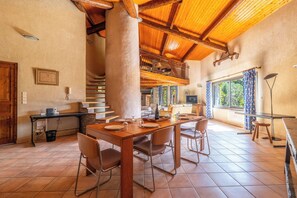 Un comedor amplio con una mesa de madera dispuesta para cuatro, una escalera que lleva a un nivel superior y un ventanal con vistas al exterior.