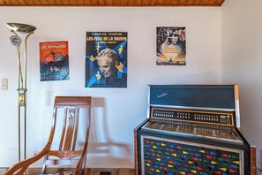 A room with a vintage radio, posters on the wall, a lamp, and a wooden chair. - Grand Mas catalan avec piscine, 12 personnes (Ille-sur-Têt)