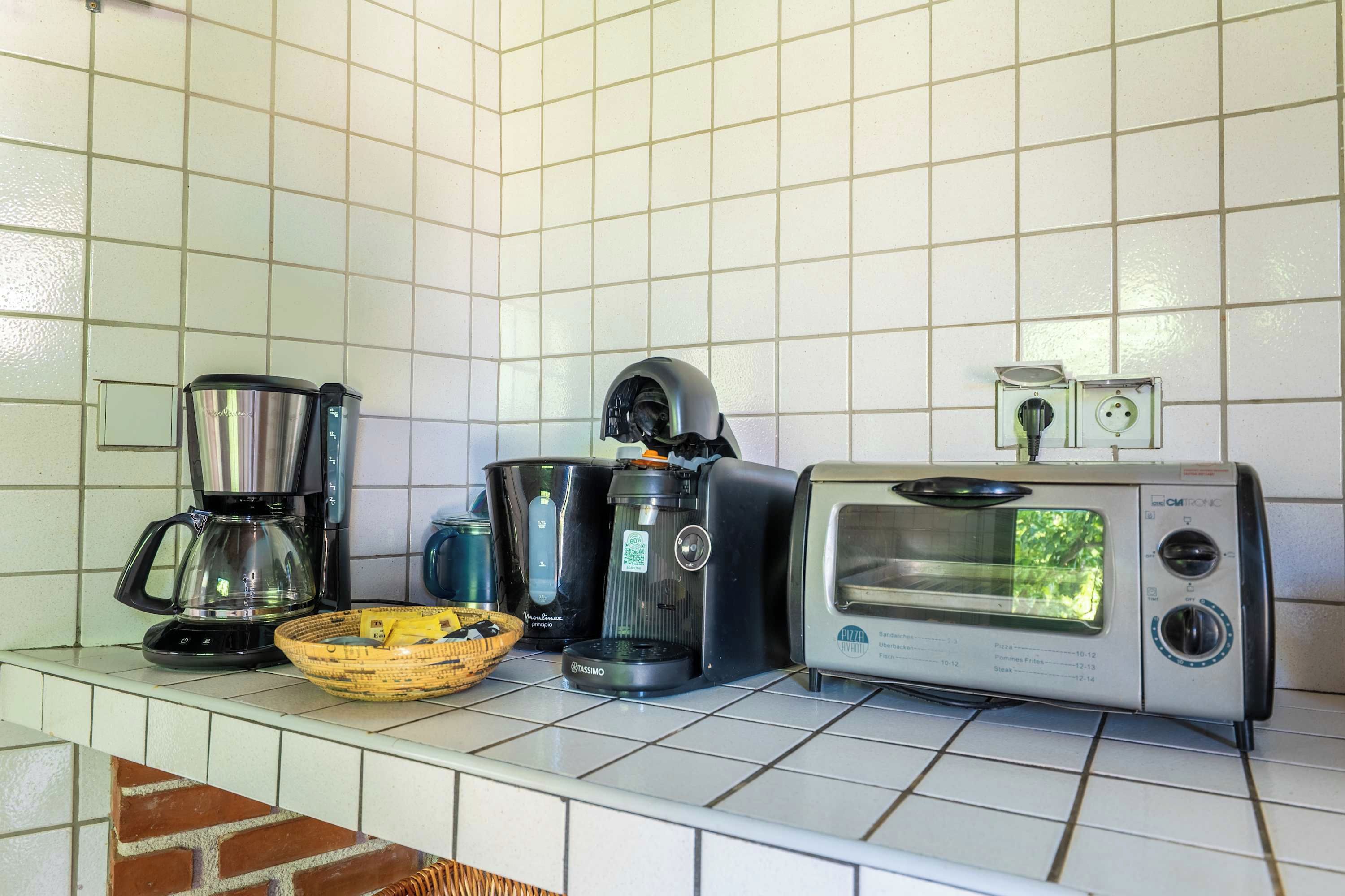 Een keuken met een koffiezetapparaat, een broodrooster en een blender op het aanrecht.